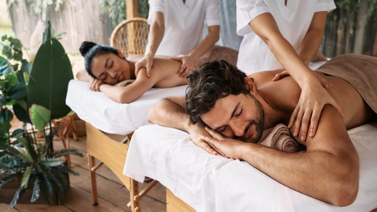 Una pareja dándose un masaje, en un lugar ideal para relajarse en pareja, rodeado de plantas y tranquilidad.